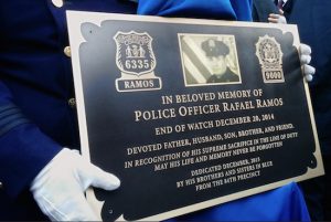 An NYPD officer holds a bronze plaque inscribed with the name of fellow officer Rafael Ramos on Sunday. AP Photo/Julie Walker
