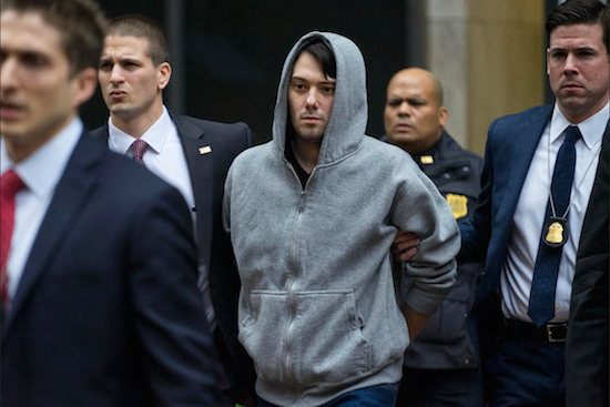 Martin Shkreli, the former hedge fund manager under fire for buying a pharmaceutical company and ratcheting up the price of a life-saving drug, is escorted by law enforcement agents in New York on Thursday after being taken into custody following a securities probe. AP Photo/Craig Ruttle