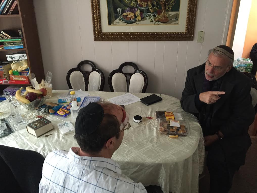 Assemblymember Dov Hikind sits with the victim of the Midwood attack at his home on Monday. Photo courtesy of the office of Assemblymember Hikind