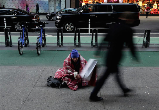 A homeless man who gave only his first name, Terry, checks his cup after a pedestrian dropped money in it near Times Square on Monday. As bitter winter temperatures finally arrived in the northeast, New York’s governor issued an executive order requiring the homeless to be forcibly removed from the street in freezing weather. AP Photo/Julie Jacobson