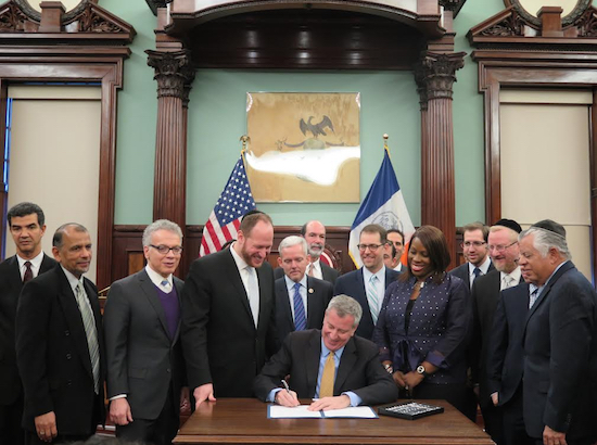 Mayor Bill de Blasio signs the non-public school security guard bill. At left, next to mayor, is Councilmember David Greenfield, the bill’s sponsor. Photo courtesy of Greenfield’s office