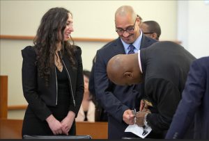 Richard Rosario, center, is joined by his lawyer Rebecca Freedman as he smiles while his handcuffs are removed in court before his conviction is overturned on Wednesday in New York. The judge overturned Rosario's murder conviction and freed him while prosecutors reinvestigate his 1996 case. AP Photo/Mary Altaffer