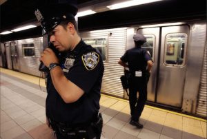 In this July 8, 2005 file photo, NYPD Officer Frank Gotay listens to a message on his radio as his partner Yolanda Cortes waits for a subway car's doors to open while performing random checks along the platform at the 42nd Street station in Manhattan. New York City transit officers can finally communicate on their radios with police above ground. AP Photo/Julie Jacobson, File