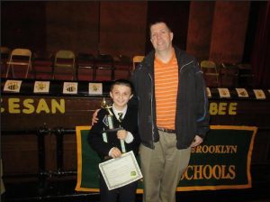 Math Bee winner James Schmidt, pictured with his proud father, also named James, picks up his championship trophy. Photo courtesy of St. Anselm Catholic Academy