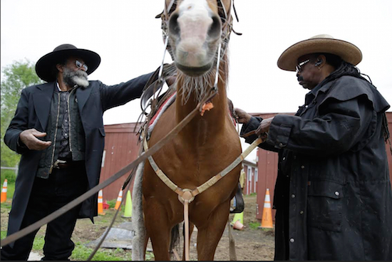 Arthur J.R. Fulmore, right, and Ellis Harris, members of the Federation of Black Cowboys, ready a horse for riding in Queens on Thursday. For decades, members of the Federation of Black Cowboys have been an incongruous sight in New York City. “When children see us with the fringe jackets and the boots, that stays with them for life,” said Kesha Morse, the federation’s 67-year-old president. But now, the federation is fighting to survive. AP Photo/Seth Wenig