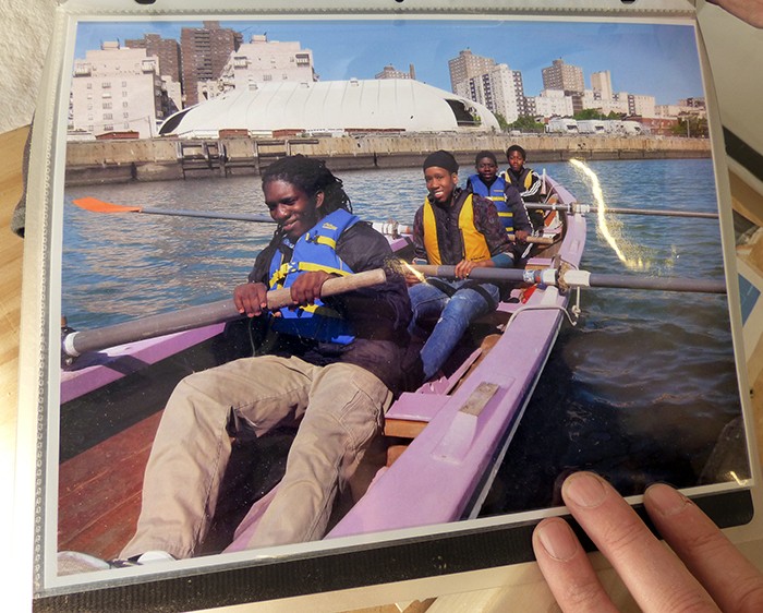 Students from Benjamin Banneker High School, who have built two boats and are working on a third, row from a dock at Wallabout Channel at the Brooklyn Navy Yard. Photo by Mary Frost, from a photo courtesy of Village Community Boathouse
