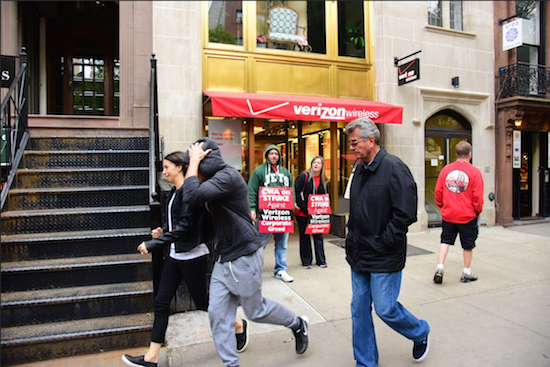 A young couple scurries away from the Verizon store on Montague Street in Brooklyn Heights amid jeers from striking CWA 1109 workers who have maintained a continuous picket at this location since the strike against Verizon began on April 13. Meanwhile, inside the store, employees played catch with a yellow tennis ball. Eagle photos by Andy Katz
