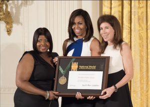 First Lady Michelle Obama (center) presents the National Medal for Museum and Library Service to the Brooklyn Public Library (BPL)  in the East Room of the White House on June 1. Accepting the award are Brooklyn Public Library community member Kim Best (left) and BPL President and CEO Linda E. Johnson. Photo by Earl Zubkoff