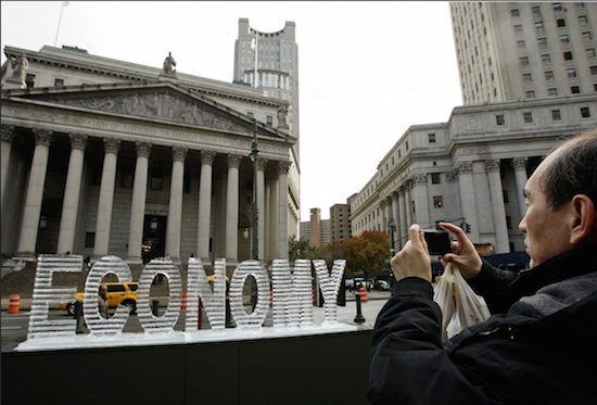 In this 2008 file photo, Nelson Lee stops in Lower Manhattan to photograph an ice sculpture titled "Main Street Meltdown," which coincided with the Black Tuesday stock market crash at the beginning of the Great Depression. The Brooklyn artists who designed the ice sculpture, Nora Ligorano and Marshall Reese, are planning two similar ice sculptures of the words “The American Dream” to go on display in Cleveland during the Republican National Convention and in Philadelphia during the Democratic National Conve