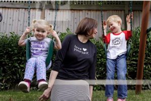 In this Thursday, July 7, 2016, photo, Courtney Hartman poses for a photo with her children Lois, 2, and Declan, 4, as they wear gender-neutral clothing of Hartman's in Seattle. Hartman owns Jessy & Jack, a collection of unisex T-shirts, and Free to Be Kids, where a shirt with the slogan, “I'm a Cat Guy” comes in blue, gray and yellow. AP Photo/Elaine Thompson