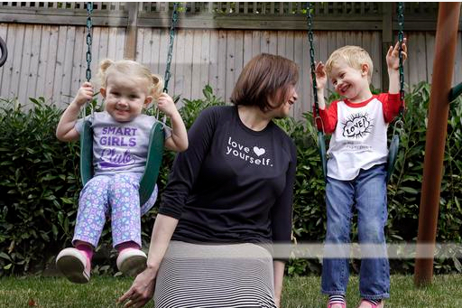 In this Thursday, July 7, 2016, photo, Courtney Hartman poses for a photo with her children Lois, 2, and Declan, 4, as they wear gender-neutral clothing of Hartman's in Seattle. Hartman owns Jessy & Jack, a collection of unisex T-shirts, and Free to Be Kids, where a shirt with the slogan, “I'm a Cat Guy” comes in blue, gray and yellow. AP Photo/Elaine Thompson