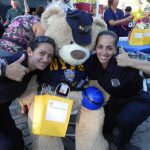 At the 2015 National Night out event, 68th Precinct Police Officers Susan Porcello (left) and Jennifer Cordero playfully posed with Capt. Ray Bear, one of the raffle prizes. Eagle file photo by Paula Katinas