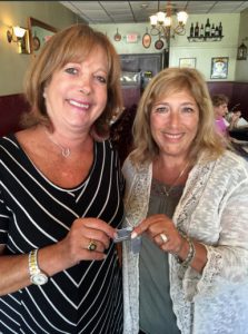 In this photo taken on Aug. 22 and provided by Audrey Berk, Berk, left, of Queens, and Laurie Lubin of Bellmore, N.Y., hold the World War II dog tags of Berk's father, Irving Isaacs in Bellmore. Lubin found the tags on a NYC beach in the summer of 1966 and spent the next 50 years trying to return them. Lubin finally tracked down Isaacs' daughter with the help of The Associated Press and gave her the dog tags at a Bellmore restaurant. Audrey Berk/Laurie Lubin/Clifford Kaplan via AP
