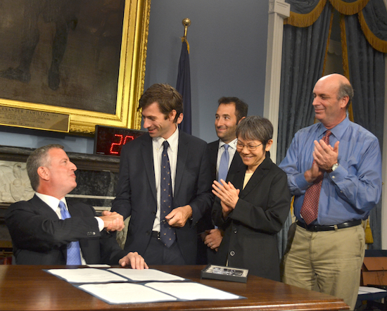 Councilmember Stephen Levin (right) congratulates Mayor Bill de Blasio at the bill signing ceremony as environmentalists look on. Photo courtesy of Levin’s office