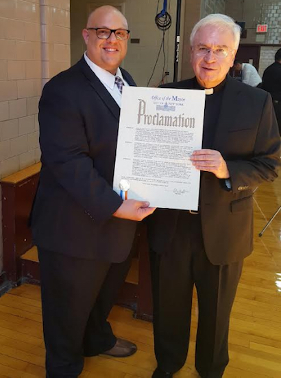 Justin Brannan (left) representing Mayor Bill de Blasio, presents a city proclamation to the Rev. Msgr. Kevin Noone, pastor of Our Lady of Angels Catholic Church, after the anniversary mass. Photo courtesy of Brannan