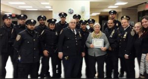 Community Board 10 Chairperson Doris Cruz (front row, fifth from right) and District Manager Josephine Beckmann (right) congratulate auxiliary police officers from the 68th Precinct. Also pictured is Capt. Joseph Hayward (third from right), the precinct commander. Photo courtesy of Board 10