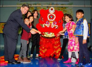 Councilmember Vincent Gentile joins P.S. 102 school children in putting the red envelope offering in the lion’s mouth. Eagle photos by Arthur De Gaeta