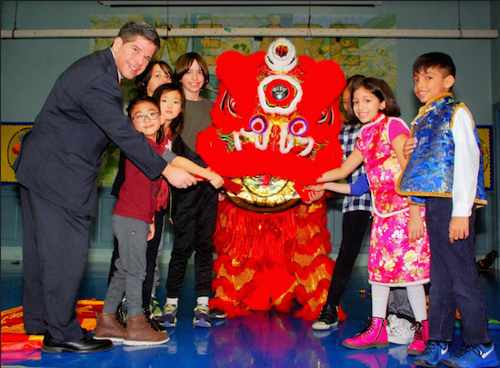 Councilmember Vincent Gentile joins P.S. 102 school children in putting the red envelope offering in the lion’s mouth. Eagle photos by Arthur De Gaeta