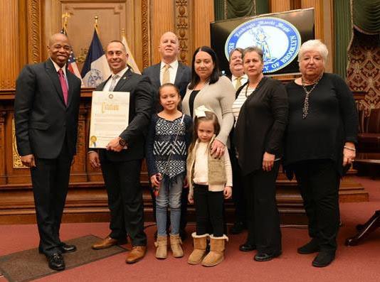 Brooklyn Borough President Eric Adams presented Lt. Detective John Russo, a Williamsburg-raised police officer whose diligence helped crack the murder case of slain jogger Karina Vetrano, as his “Hero of the Month” for February at a ceremony in the courtroom of Brooklyn Borough Hall; they were joined by NYC Police Commissioner James O’Neill (center, left) and members of Russo’s family. Photo Credit: Erica Sherman/Brooklyn BP’s Office