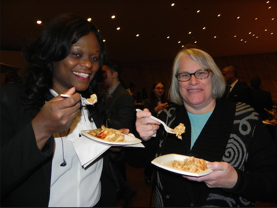 Assemblymembers Rodneyse Bichotte (left) and Helene Weinstein enjoy tasting lasagna. Eagle photos by Paula Katinas