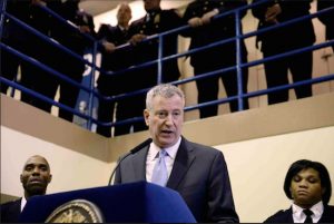 In this March 12, 2015 file photo, New York Mayor Bill de Blasio is surrounded by corrections officers as he speaks at a news conference at the Rikers Island prison in New York. Gov. Andrew Cuomo and some activists say shutting down Rikers is the only solution for a cycle of abuses that includes violence by guards and gang members, mistreatment of the mentally ill and juveniles and unjustly long detention for minor offenders. But de Blasio is against a shutdown, saying reforms and improvements would cost le