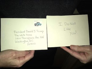 A Brooklyn resident displays her postcard to President Donald Trump, part of a nationwide campaign called The Ides of Trump. Photo by Mary Frost