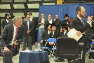 Mayor Bill de Blasio (left) and Councilmember David Greenfield (standing) both listen intently to a question at the Borough Park town hall. Photo courtesy of Greenfield’s office