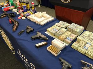 Cash earned by the heroin drug ring next to guns that were used to protect the business. Eagle photo by Paul Frangipane
