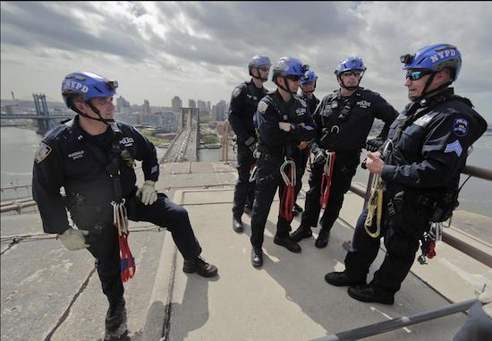 NYPD sergeant John Flynn, right, briefs several Emergency Services Unit officers during a training exercise on top of the Brooklyn Bridge. Dizzying heights that would terrify most people are as comfortable as a playground jungle gym to Flynn and other members of an elite police unit that specializes in dangerous, often high-rise rescues. AP Photos/Julie Jacobson