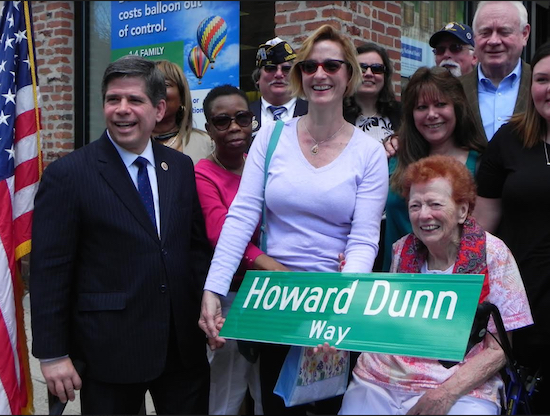 Mae Dunn (seated) and her daughter Geraldine Martinez hold a replica of the street sign bearing Howard Dunn’s name. At left is Councilmember Vincent Gentile. Eagle photo by Paula Katinas