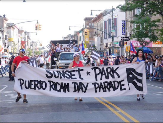 Marchers hold a banner at the front of the Third Annual Sunset Park Puerto Rican Day Parade. Eagle photos by Arthur De Gaeta