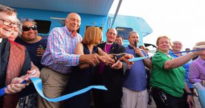 From: left: Norm Brodsky, Elaine Brodsky and Bishop Lawrence C. Provenzano work the scissors to cut the ribbon and officially launch the North Brooklyn Angelmobile. Brooklyn Eagle Photos by Andy Katz
