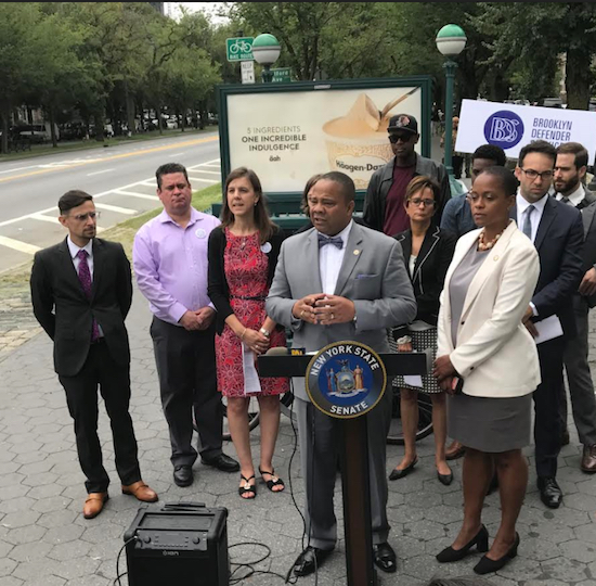 State Sen. Jesse Hamilton (at podium) and Assemblymember Tremaine Wright (right) speak at a press conference outside the Franklin Ave subway station, where they were joined by transit and criminal justice reform advocates. Photo courtesy of Hamilton’s office