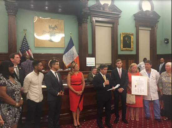 Mark Kindschuh accepts congratulations from Councilmember Vincent Gentile (at microphone) during a ceremony in the City Council chambers. Council Speaker Melissa Mark-Viverito and members of the council’s Brooklyn delegation attended the ceremony. Photo courtesy of Gentile’s office