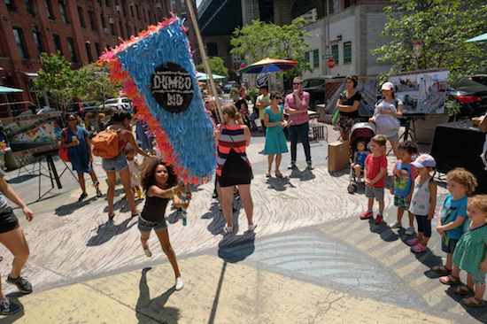 A young girl takes her shot at hitting the DUMBO BID piñata at The Pearl Street Triangle. Photos by Gabriella Bass