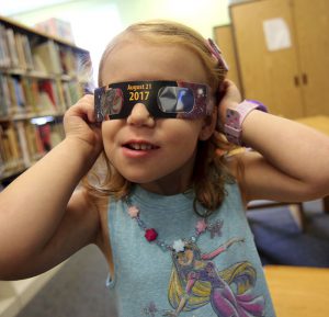To view this Monday’s solar eclipse, you must wear special ISO approved glasses. Shown: Emmalyn Johnson, 3, tries on her free pair of eclipse glasses at Mauney Memorial Library in Kings Mountain, N.C. on Wednesday.  Brittany Randolph/The Star via AP