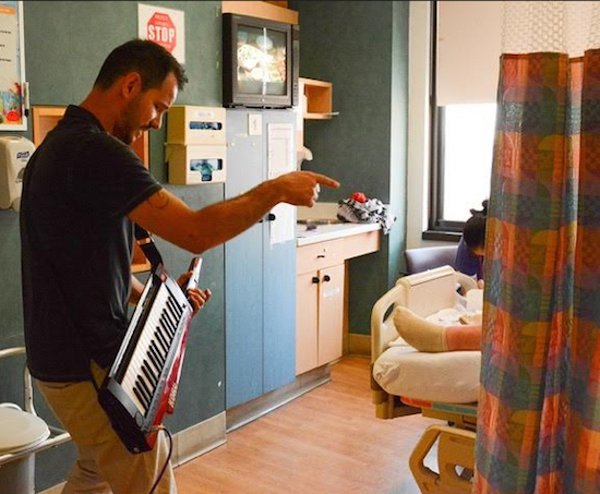 Music That Heals musician and singer David Diedrich plays his keytar for a hospital patient. Photo courtesy of Kathy Lord