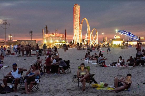 In this July 21 photo, families enjoy an evening on the beach in Coney Island. Coney Island is a storied place, known for Nathan’s hot dogs, old-fashioned amusement park rides and a gritty beach. But after sundown it has a different feel. With the crowds and tourists mostly gone, locals come out to enjoy balmy summer evenings as the heat of the day subsides. AP Photos/Mark Lennihan