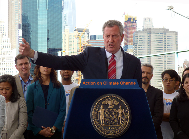 “The number one problem is those buildings you see behind me,” de Blasio said at Brooklyn Bridge Park on Thursday, as he announced new rules that would force thousands of building owners to retrofit their boilers, windows and roofs in order to make sharp reductions in greenhouse gas emissions.  Eagle photo by Mary Frost