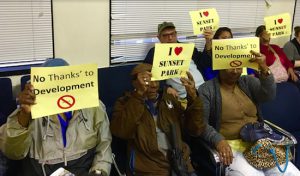 Attendees at a Department of City Planning hearing hold signs expressing their opinions about the proposed expansion of Industry City. Eagle photos by Lore Croghan