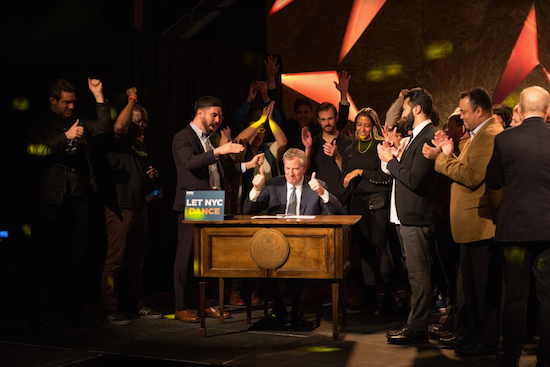 Mayor Bill de Blasio (center) and Councilmember Rafael Espinal (left) celebrate the signing of legislation that repealed the Cabaret Law. Courtesy of NYC Mayor’s Office