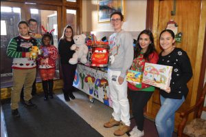 Head of School Iphigenia Romanos (fourth from left) and Student Advisory Board members Anthony Iglesias, Arber Kadiu, Ania John, Andre Pantaleo, Regina Levy and Natalie Fabian (left to right) present some of the toys that students and teachers collected and distributed this holiday season. Photo courtesy of Adelphi Academy of Brooklyn