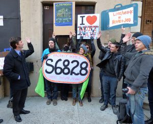 Councilmember Stephen Levin, left, asks residents of 79 Lorimer St. to raise their hands at a press conference Tuesday morning. The sign labeled S6828 refers to Senate bill S6828, which would amend the loft laws. Photo by Mary Frost