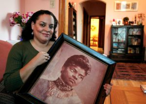 FILE - In this Dec. 2, 2011 file photo, Michelle Duster, great-granddaughter of civil rights pioneer Ida B. Wells who led a crusade against lynching during the early 20th century, holds a portrait of Wells in her home in Chicago's South Side.  AP Photo/Charles Rex Arbogast, File