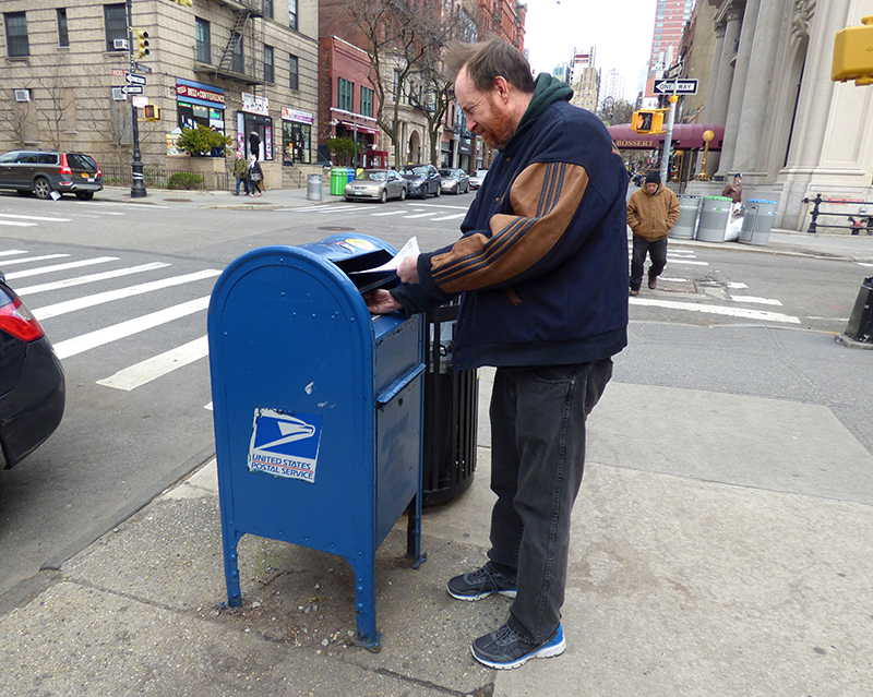 William Balardelle mails a letter in the USPS collection box at the corner of Montague and Henry streets in Brooklyn Heights. That’s one of several mailboxes in the neighborhood that have recently been targeted by thieves in a scam called mailbox fishing. Photo by Mary Frost