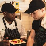 Emma’s Torch, a nonprofit that empowers refugees, asylees and survivors of human trafficking through culinary education, recently opened at 345 Smith St. Shown: Culinary director Alexander Harris speaks with a student. Photos by Giada Randaccio Skouras Sweeny