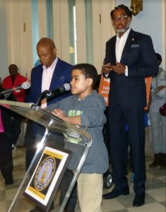 Seventh-grader Giovanni Santana, a student at Bedford-Stuyvesant’s New Beginnings Charter School, said his school should get funds for security guards, too. Behind Giovanni is Brooklyn Borough President Eric Adams (left) and Councilmember Robert Cornegy Jr. Eagle photo by Mary Frost