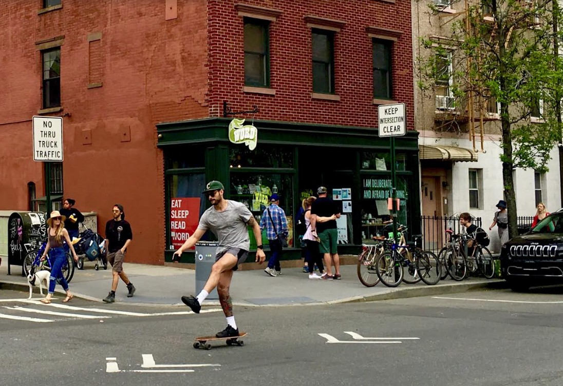 A grownup on a skateboard glides past Word, a Franklin Street bookstore.