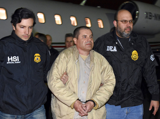 In this  2017 file photo provided by U.S. law enforcement, authorities escort Mexican drug lord Joaquin "El Chapo" Guzman, center, from a plane in Ronkonkoma, N.Y. A judge has postponed the New York trial of Guzman until November 2018. U.S. law enforcement via AP, File