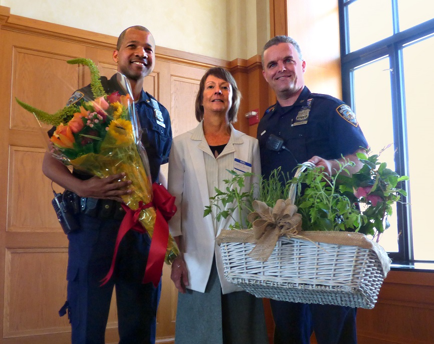 84th Precinct Neighborhood Coordination Officers Donovan Hunt (left) and John Condon were presented with flowers by Montague Street BID Executive Director Kate Chura on Thursday. Eagle photo by Mary Frost